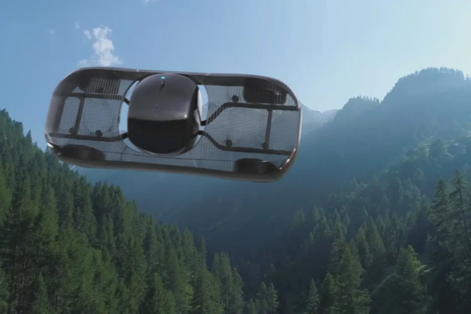A conceptual rendering of a flying car, pictured in flight over mountains.